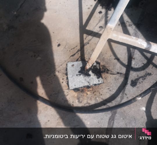 A metal pole sealed to a concrete surface with black sealant.